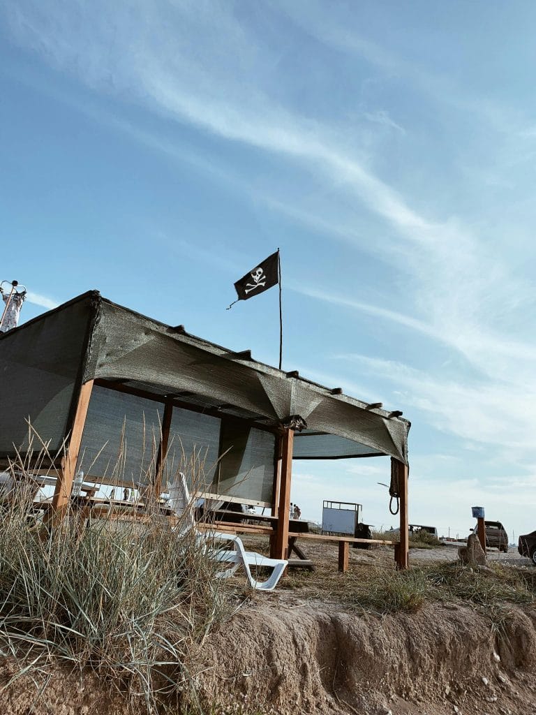 A Hut on a beach flying the Jolly Roger pirate flag