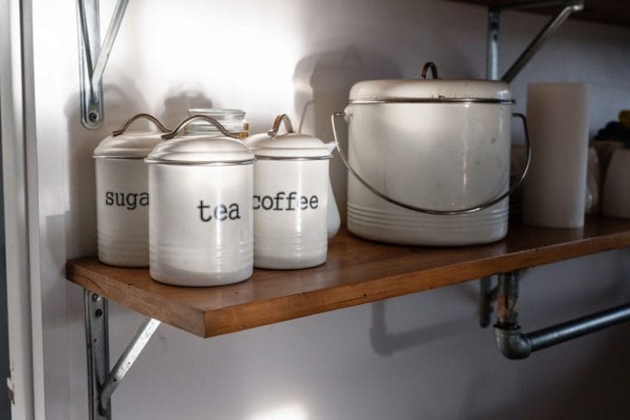 Rustic farmhouse pantry with glass jars of whole ingredients on wooden shelves in warm morning light.