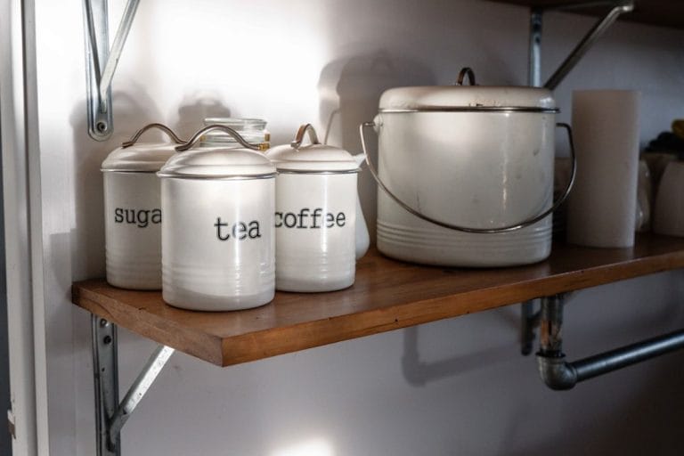 Rustic farmhouse pantry with glass jars of whole ingredients on wooden shelves in warm morning light.