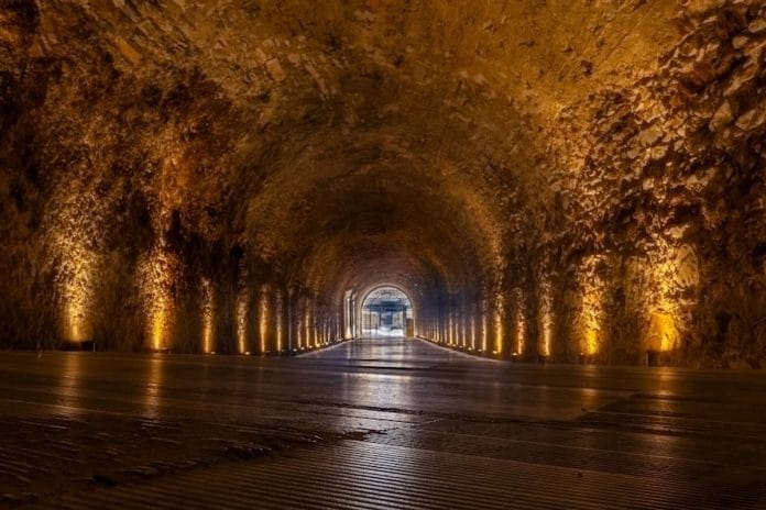 An empty stadium tunnel lit by overhead lights after a night NFL game, with confetti on the concrete.
