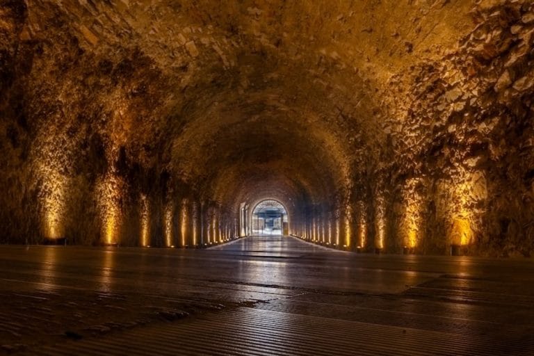 An empty stadium tunnel lit by overhead lights after a night NFL game, with confetti on the concrete.