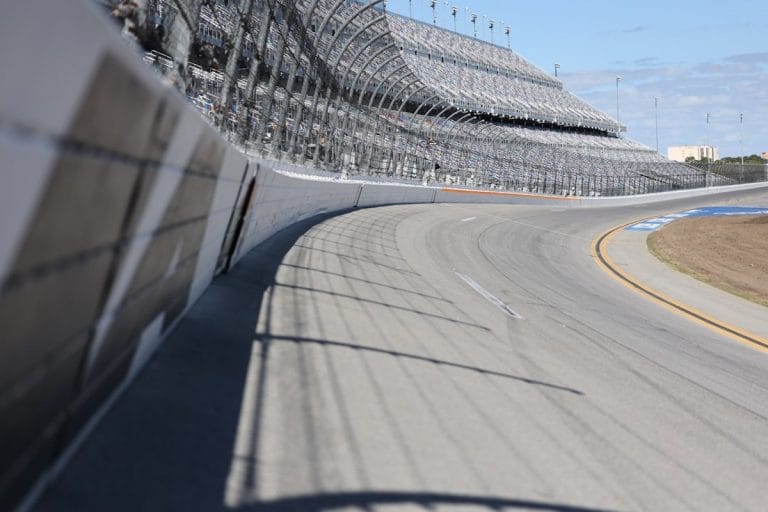 A NASCAR stock car racing through a banked turn at Daytona International Speedway