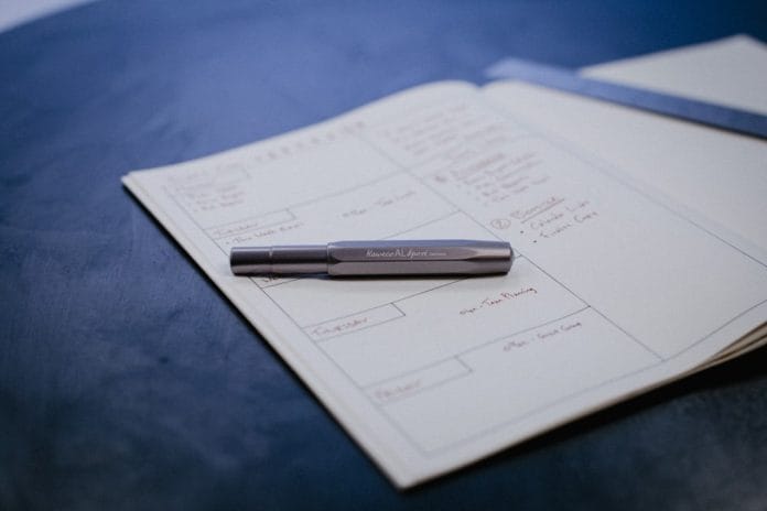 A printed NCAA tournament bracket on a kitchen table, partially filled in with pencil