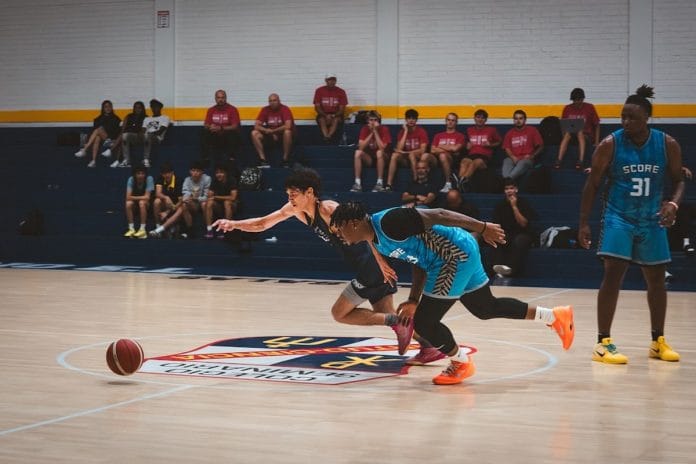 A small-college basketball game in a packed mid-sized arena, fans leaning forward in the stands