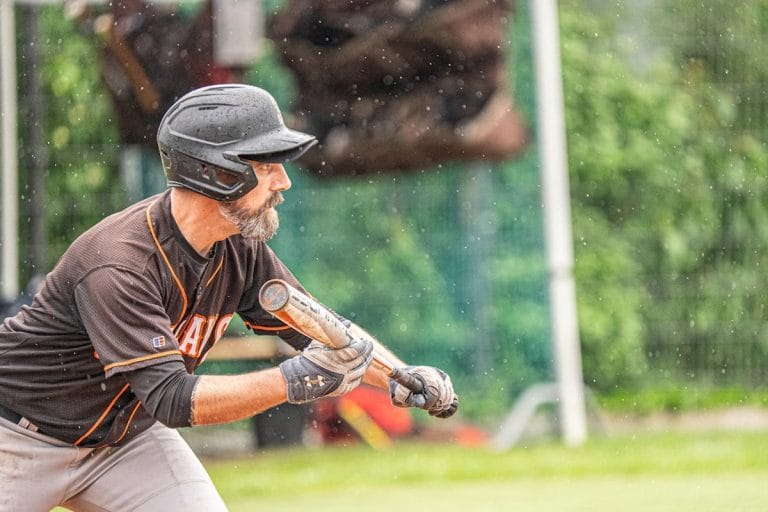 A batter mid-swing at home plate under stadium lights, ball just off the bat