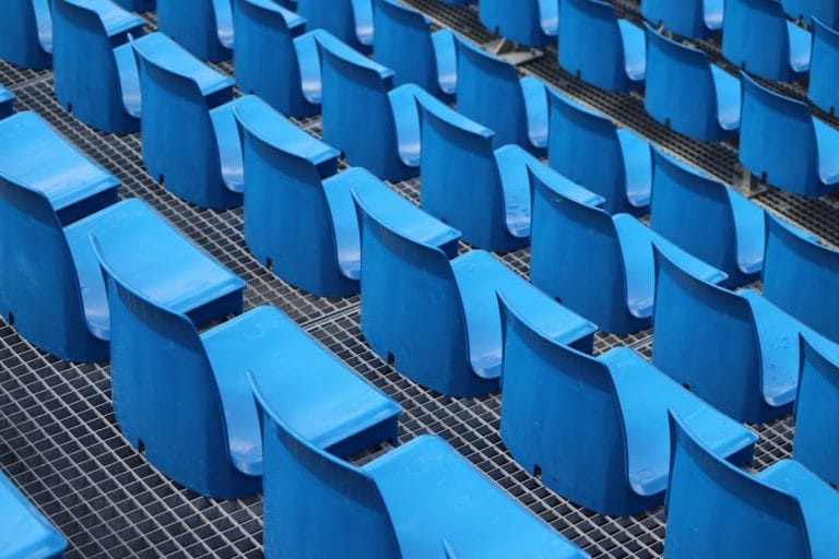 An NFL sideline bench sits empty during a preseason game under stadium lights.