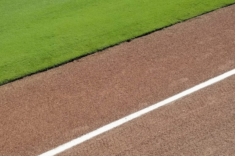 A mostly empty baseball stadium during a weekday afternoon game, sun on the upper deck, a few scattered fans in the lower bowl.