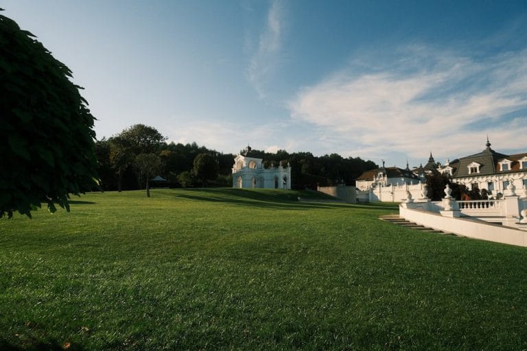 Rows of empty white folding chairs arranged on a sunlit lawn for an outdoor wedding ceremony