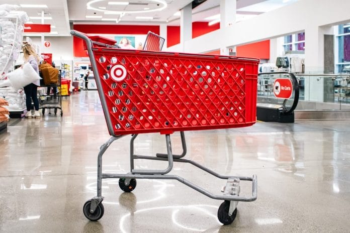 A picked-over clearance rack inside a department store after the holidays, with hangers spaced unevenly and red sale tags visible.
