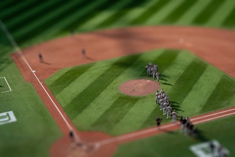 A baseball manager walks slowly to the pitcher's mound during a night game, signaling to the bullpen.