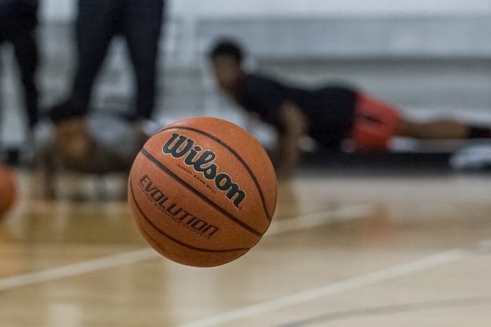 A wide view of an NBA arena floor after a game, with stage lighting and confetti remnants visible at center court.