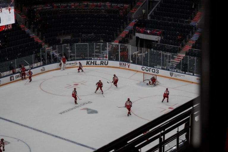 Two women's ice hockey players battle for the puck along the boards during a fast-paced game.