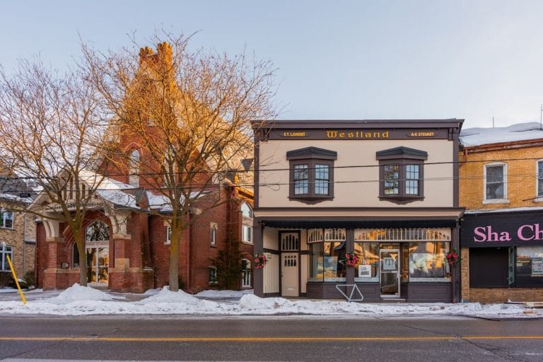 A modest small-town funeral home with a sign out front, late afternoon light