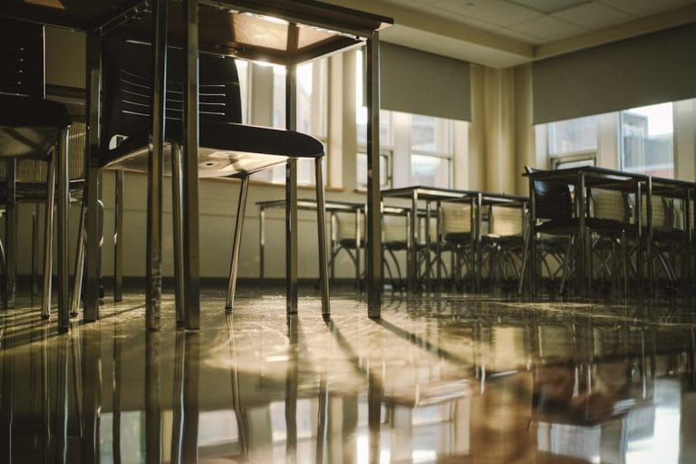 Small wooden chairs and a low table in a quiet daycare classroom, late afternoon light through the windows.