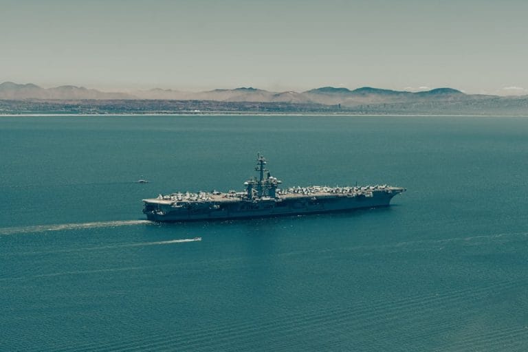 A United States Navy aircraft carrier underway on open water, photographed from a low angle showing the flight deck and superstructure.